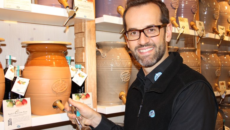 Ein Mann füllt eine Flasche aus einem großen Keramikfass bei Vom Fass.