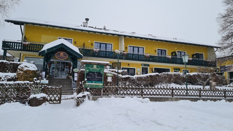 Yellow building in the snow with green veranda and entrance.