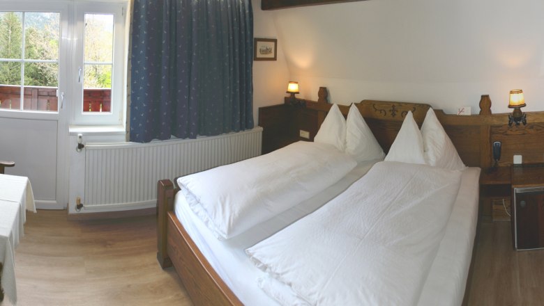 Gemütliches Schlafzimmer mit Doppelbett, Holzmöbeln und Fenster mit Blick ins Grüne.