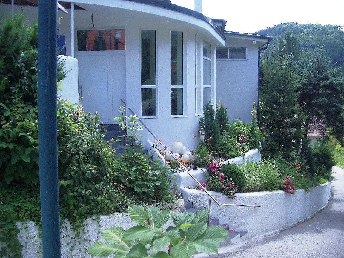 Eingang eines modernen Gebäudes mit Garten und Treppe.