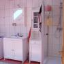 Bathroom with washing machine, washbasin, mirror and shower.