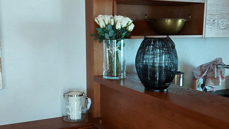 Wooden kitchen with shelves, cushions and decorations.
