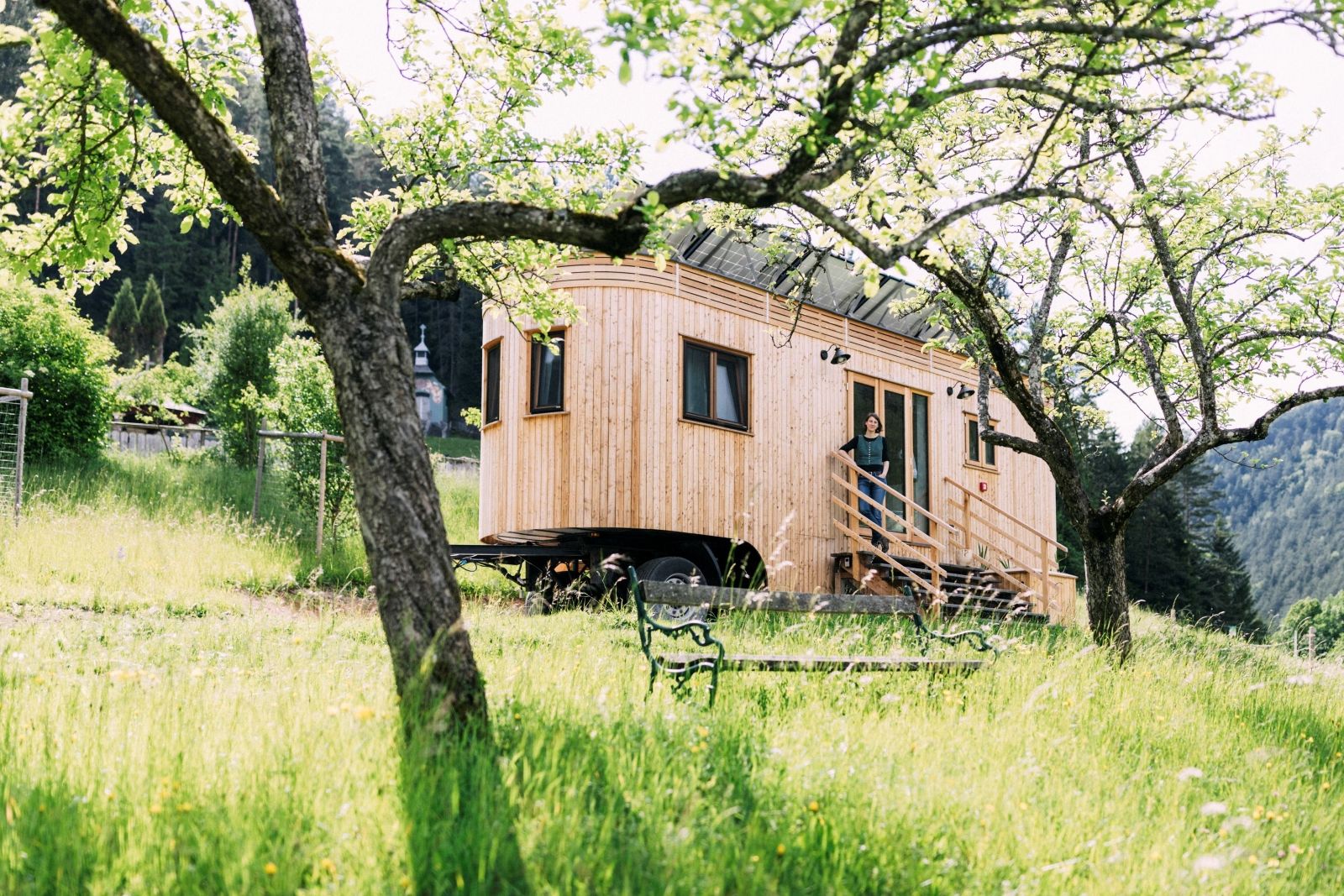 Wohnwagon steht in der Natur zwischen Bäumen und Wiesen 