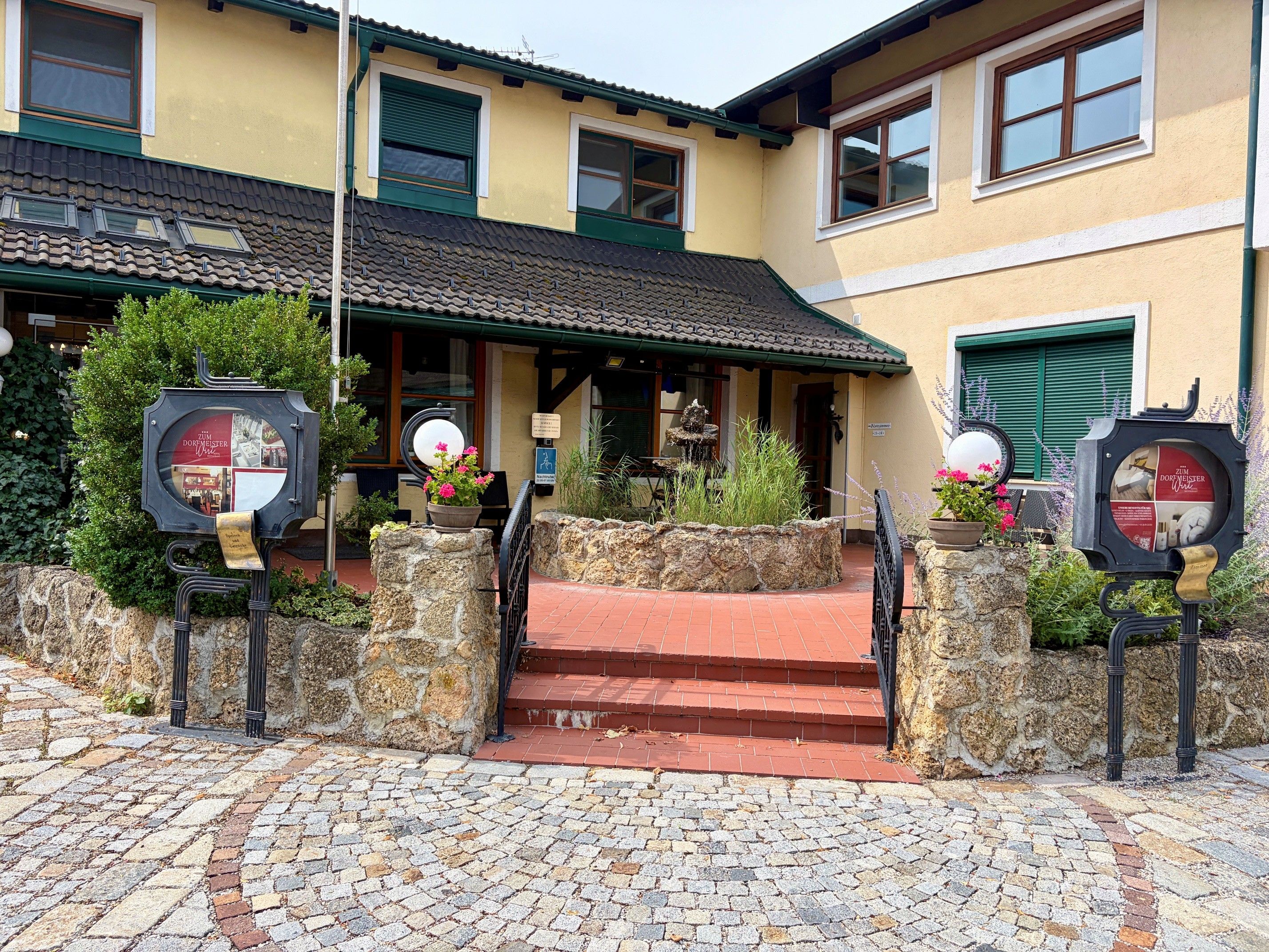 Entrance to the Dorfmeister Business Hotel, featuring cobblestones and plants.