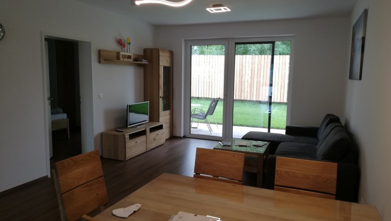 Modern living room with wooden furniture, gray sofa and large window overlooking the garden.