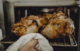 Frisch gebratenes Schweinefleisch wird aus dem Ofen genommen.