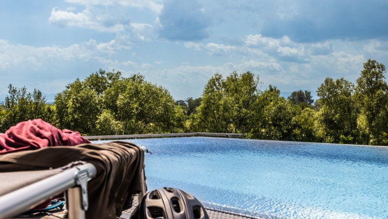 Ein Infinity-Pool mit Bäumen im Hintergrund und einem Fahrradhelm im Vordergrund.