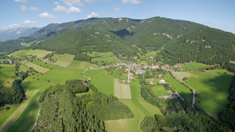Aerial view of the municipality of Prigglitz with green fields and forests, surrounded by hills.