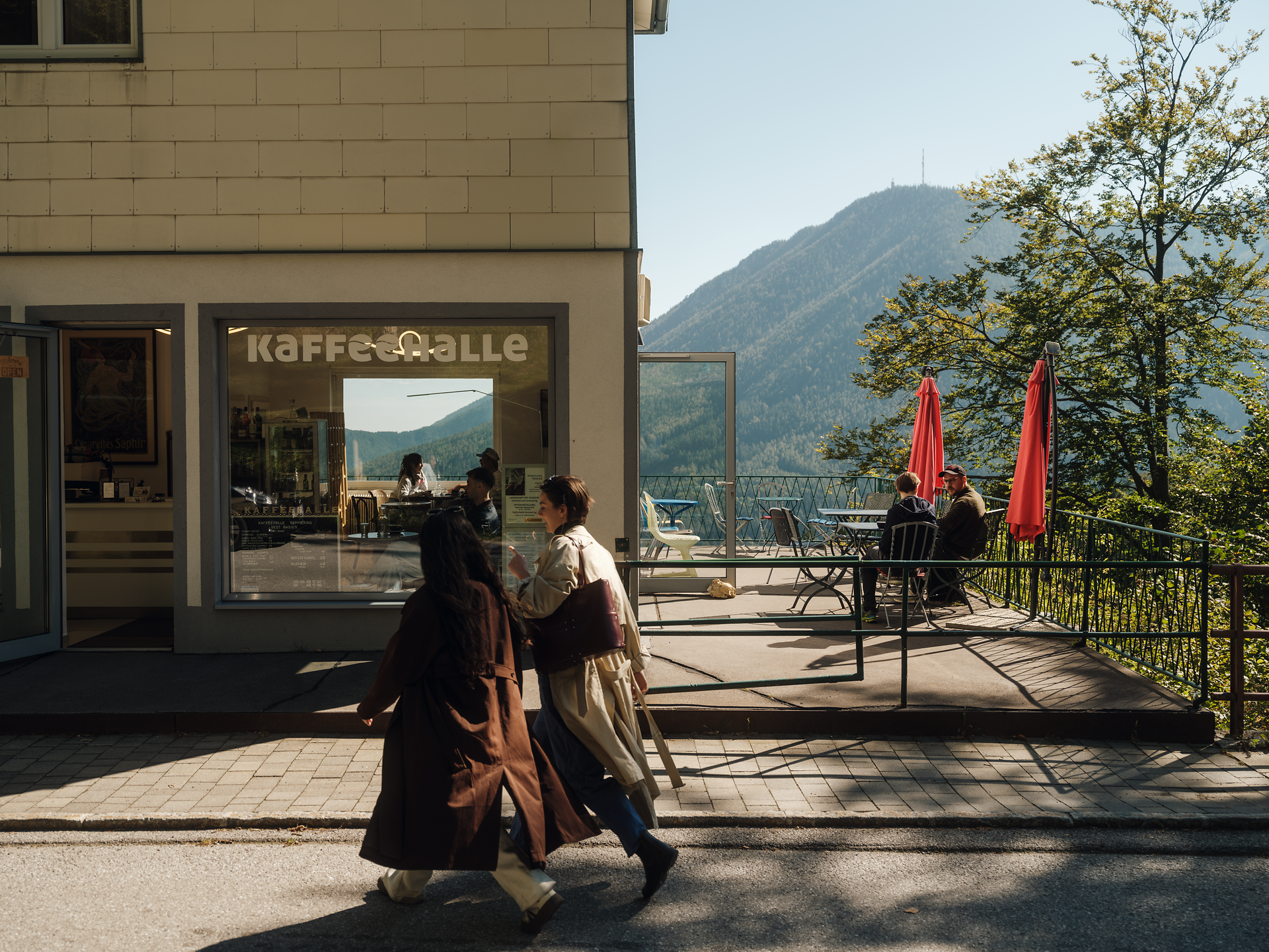 Die Sonne strahlt über die malerische Terrasse, wo Besucher die atemberaubende Aussicht auf die umliegenden Berge genießen. Gemütliche Sitzgelegenheiten laden dazu ein, bei einer Tasse Kaffee die frische Bergluft zu atmen und die Ruhe der Natur zu erleben.