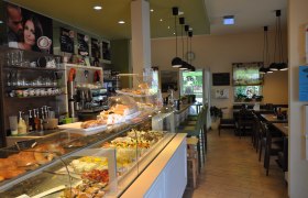 Interior view of a caf&eacute; with counter full of pastries and seating area.
