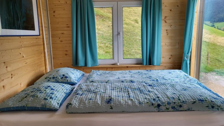 Wooden interior with bed, window and blue curtains.