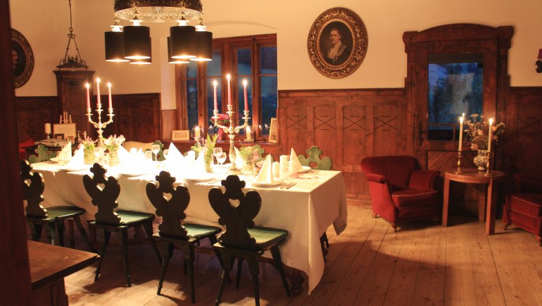 Elegantes Speisezimmer mit gedecktem Tisch, Kerzenleuchtern und antiken Möbeln.