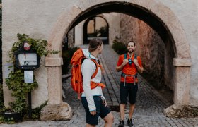 Zwei Wanderer stehen am Eingangstor zum Schloss Gloggnitz