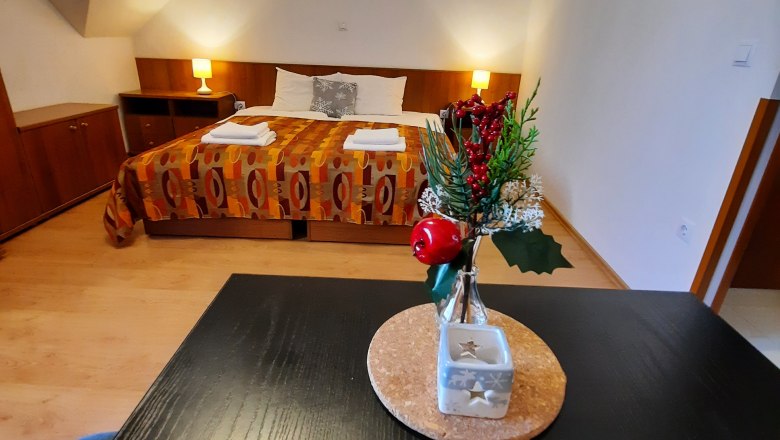 Ein gem&uuml;tliches Doppelzimmer mit einem dekorierten Tisch im Vordergrund und einem Bett im Hintergrund.