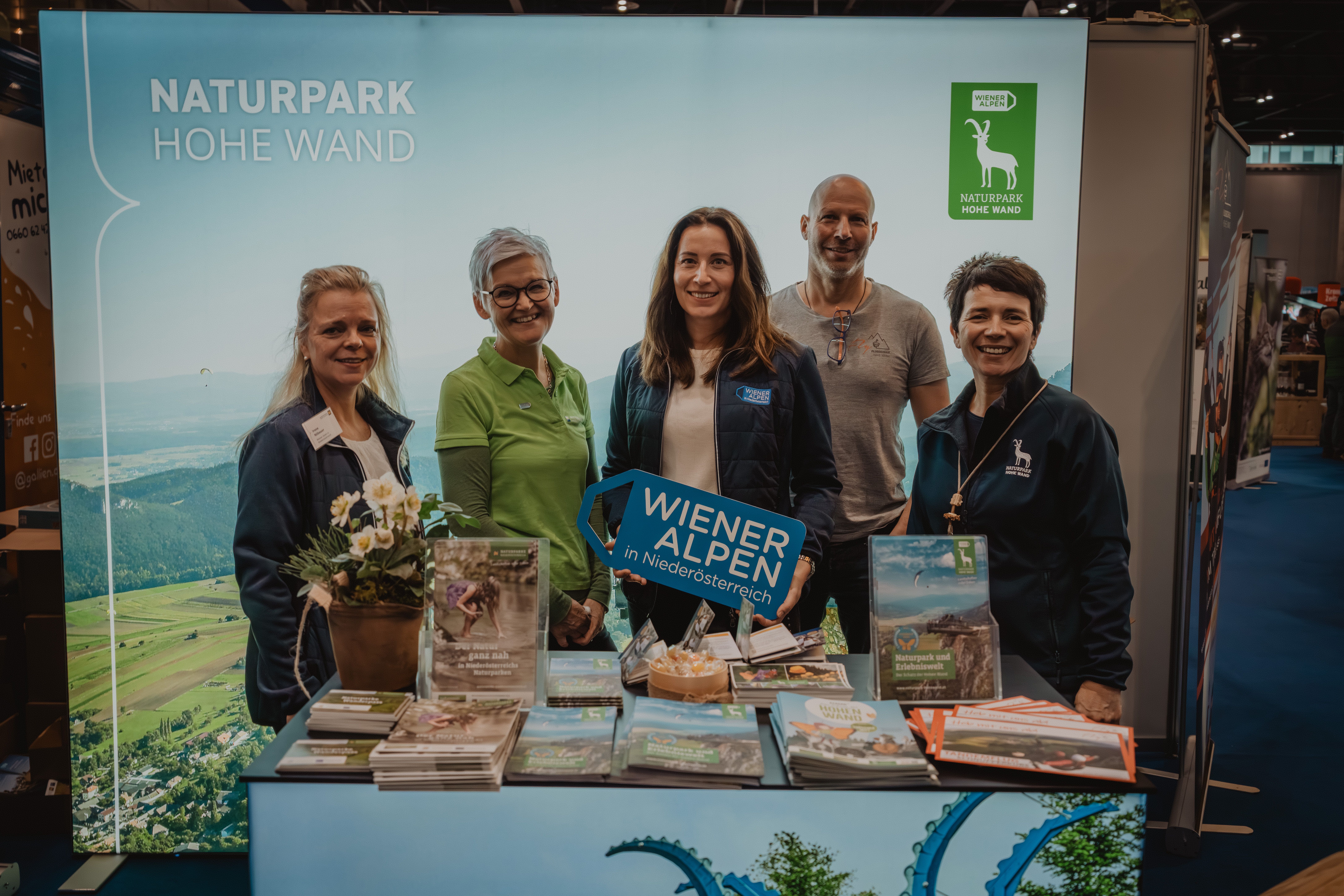 Fünf Personen mit dem Schild Wiener Alpen in Niederösterreich vor dem Stand Naturpark Hohe Wand 