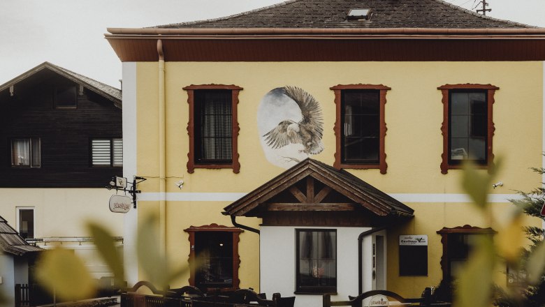 Gasthof Schwarzer Adler, © Niederösterreich Werbung/Sophie Menegaldo Gelbes Gebäude mit Wandgemälde eines Adlers und roten Fensterrahmen.