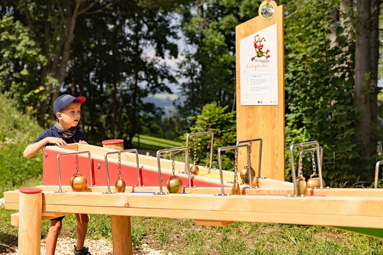 Ein Junge spielt an einer hölzernen Kugelbahn im Freien.