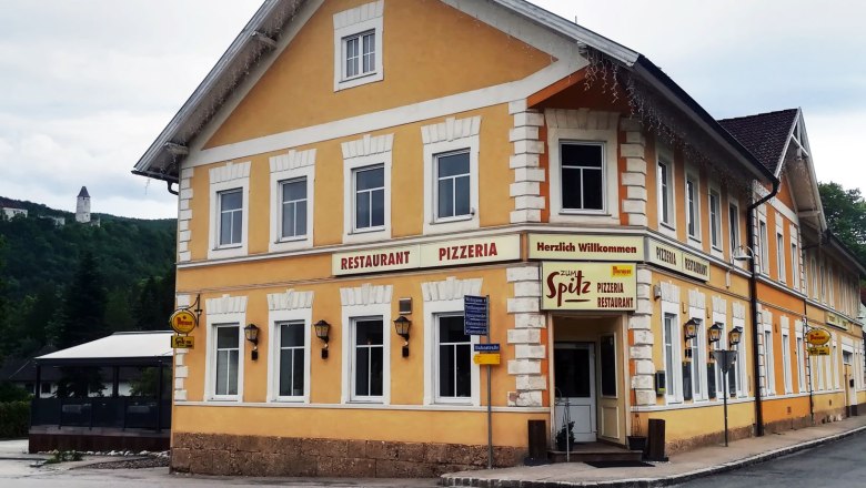 Gelbes Gebäude mit der Aufschrift 'Restaurant Pizzeria Zum Spitz'.