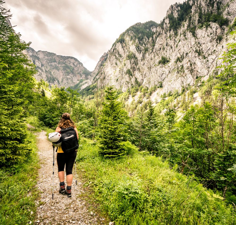 Ein Wanderer genießt die frische Bergluft und die atemberaubende Aussicht auf die majestätischen Felsen und üppigen Wälder des Höllentals. Der schmale Pfad führt durch eine grüne Oase, wo das Zwitschern der Vögel und das Rauschen des Windes eine harmonische Melodie bilden. Hier, inmitten der Natur, wird jeder Schritt zu einem unvergesslichen Erlebnis.