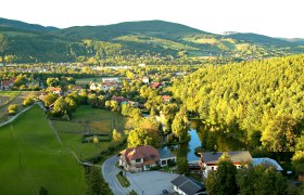 Landschaftsansicht von Enzenreith mit H&auml;usern, W&auml;ldern und H&uuml;geln im Hintergrund.
