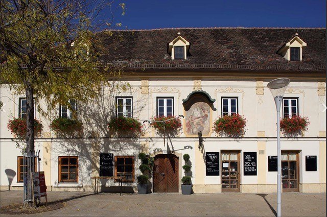 Historisches Gebäude mit Blumenkästen und Wandgemälde.