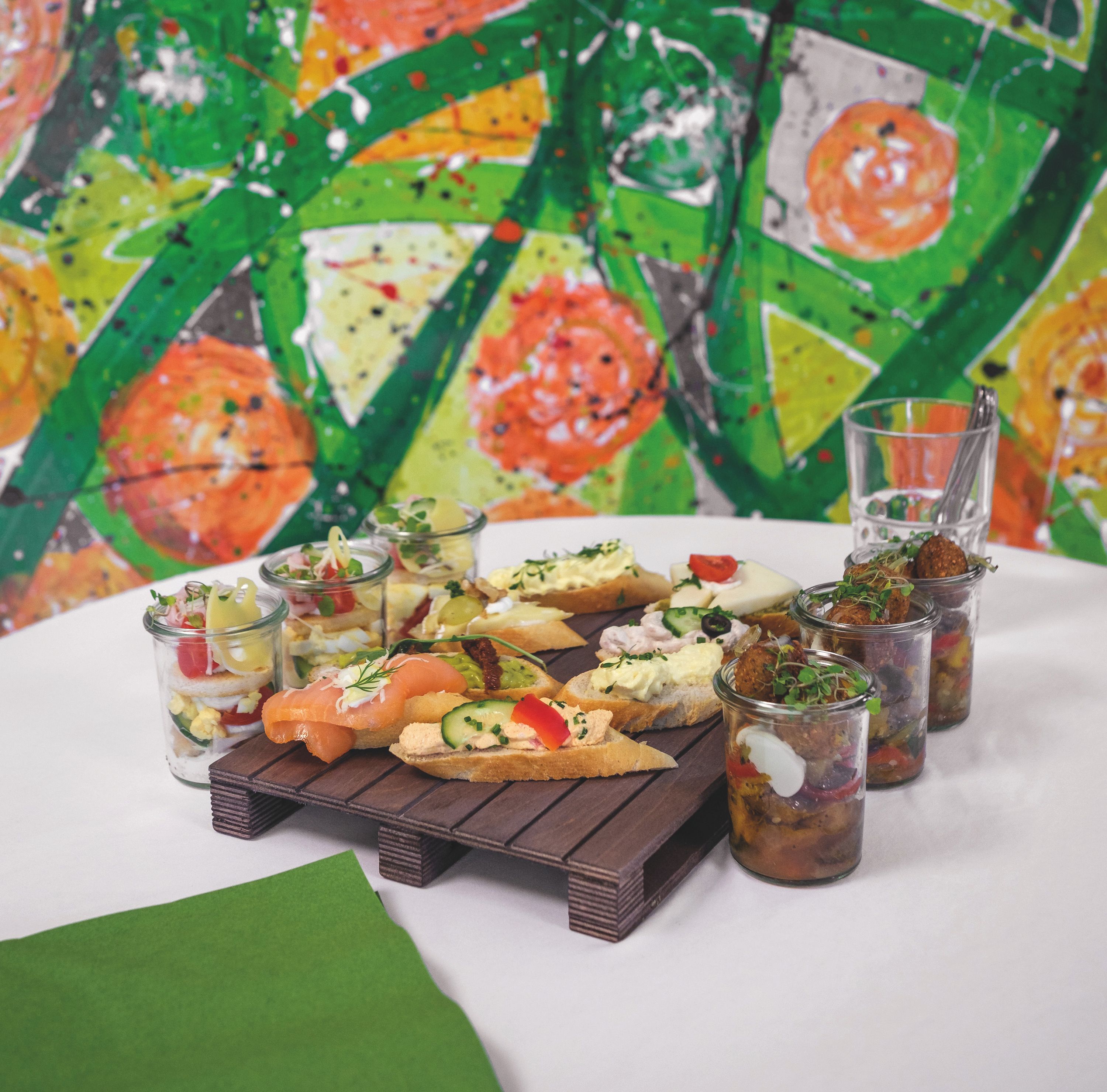 Diverse Brötchen mit Lachs, Frischkäse, Gemüse und anderen Belägen, und kleine Schälchen mit Antipasti