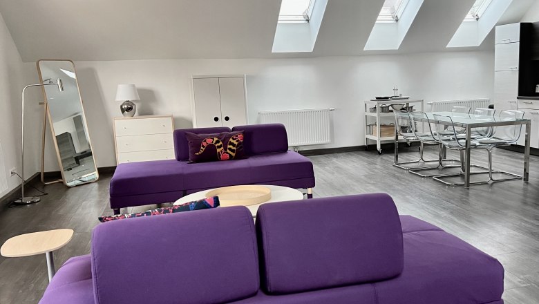 Modernes Loft mit lila Sofas, Esstisch und Dachfenstern.