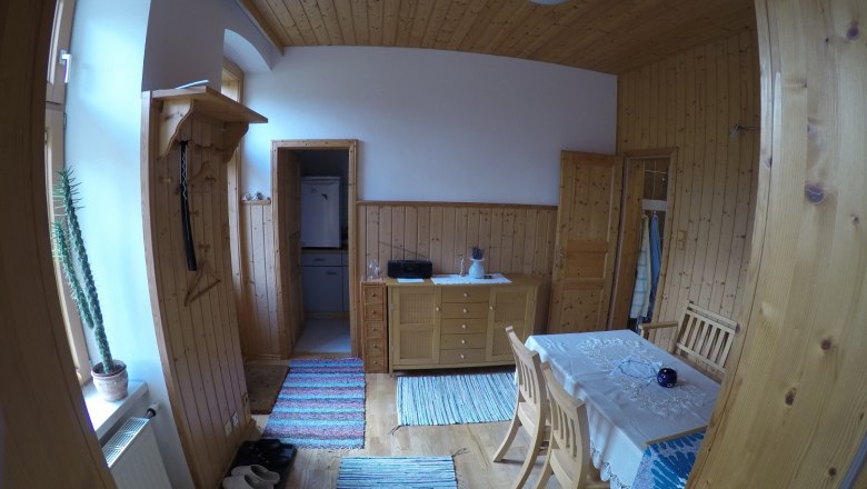 Esszimmer in einer Ferienwohnung mit Holzwänden, Esstisch, Stühlen und Teppichen.