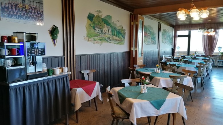 Innenansicht eines Restaurants mit Holzmöbeln und Tischdecken.