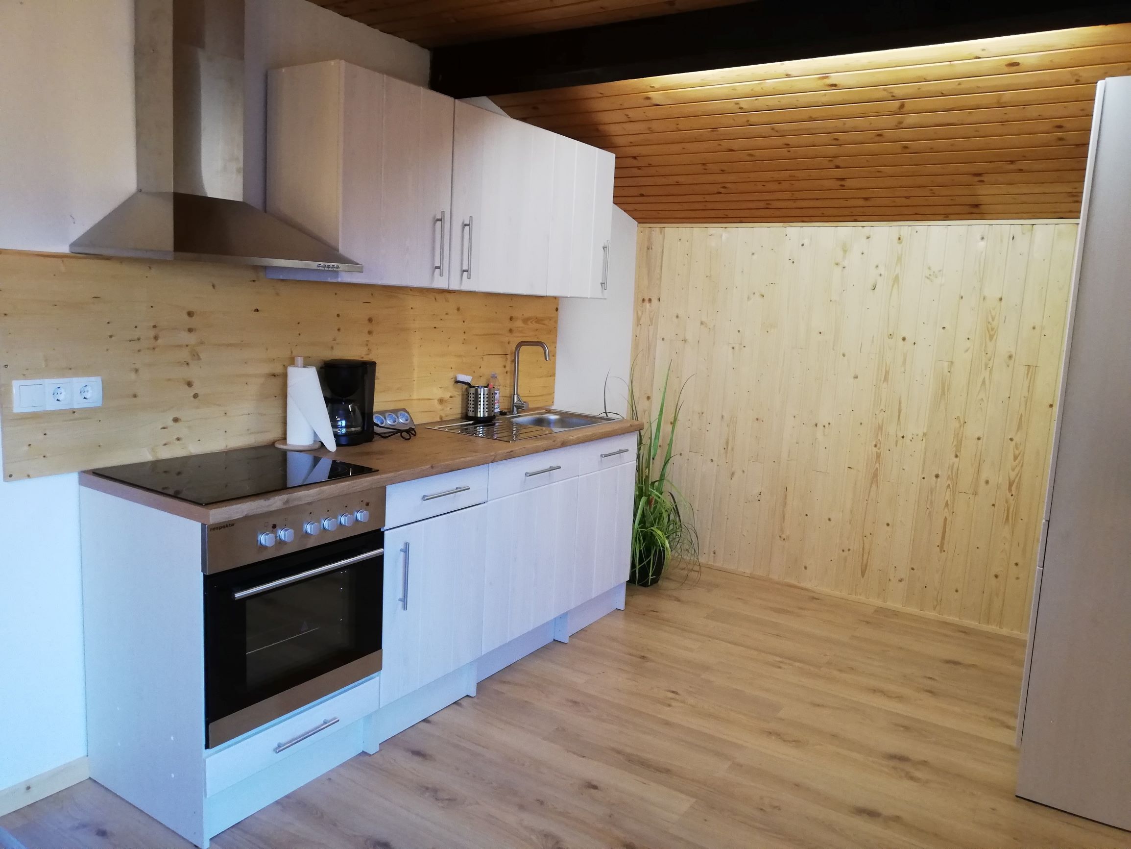 Moderne Küche in einem Dachgeschoss mit Holzverkleidung und Geräten.