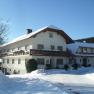 Ein gro&szlig;es Bauernhaus im Winter mit Schnee bedeckt, unter blauem Himmel.