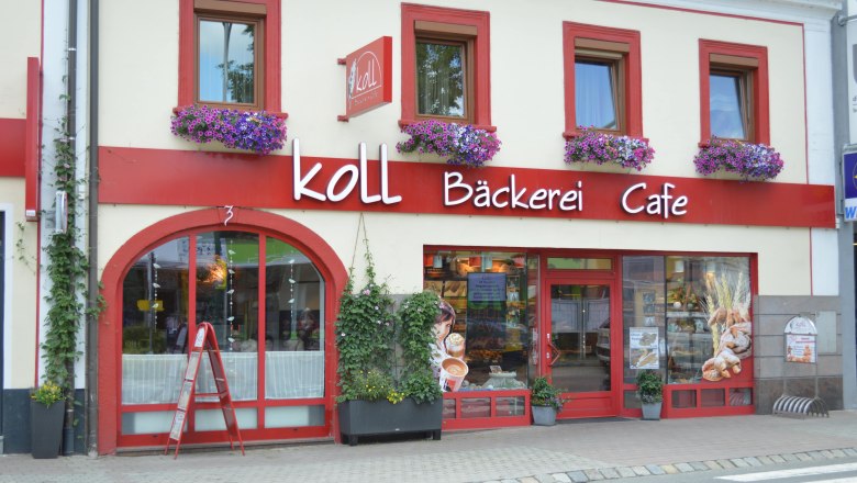 Exterior view of the Koll B&auml;ckerei Caf&eacute; in Kirchschlag with red window frames and flower boxes.