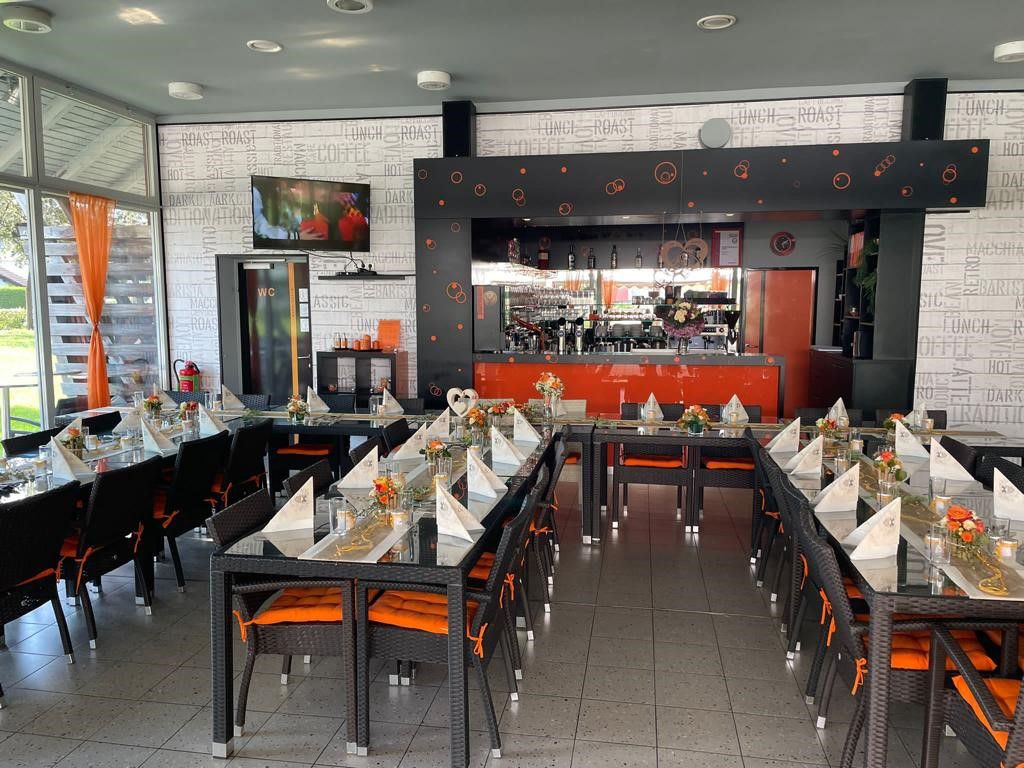 Ein stilvoll eingerichtetes Café mit gedeckten Tischen und einer Bar im Hintergrund.