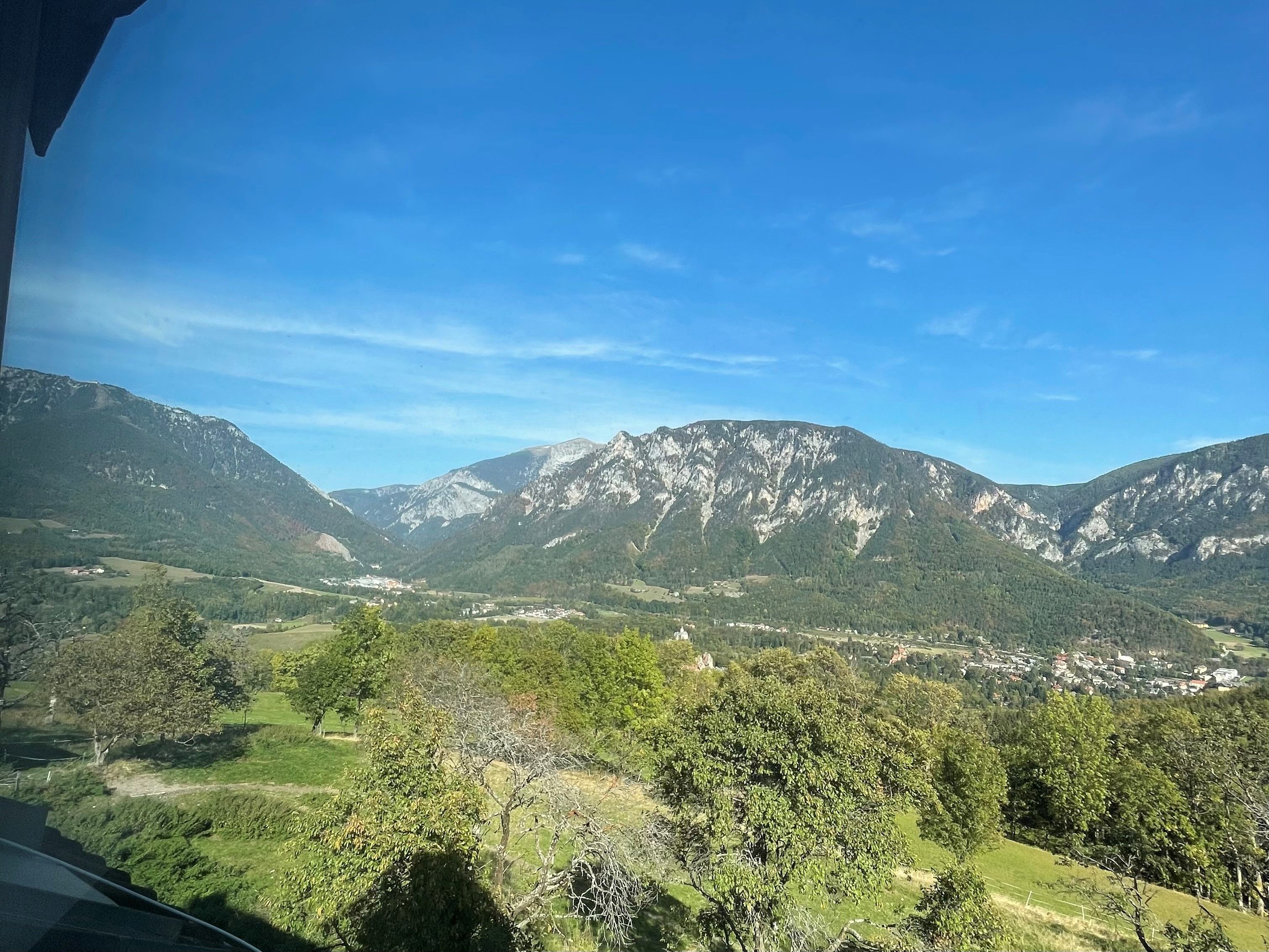 Blick auf eine Berglandschaft mit blauem Himmel und grünen Wiesen.