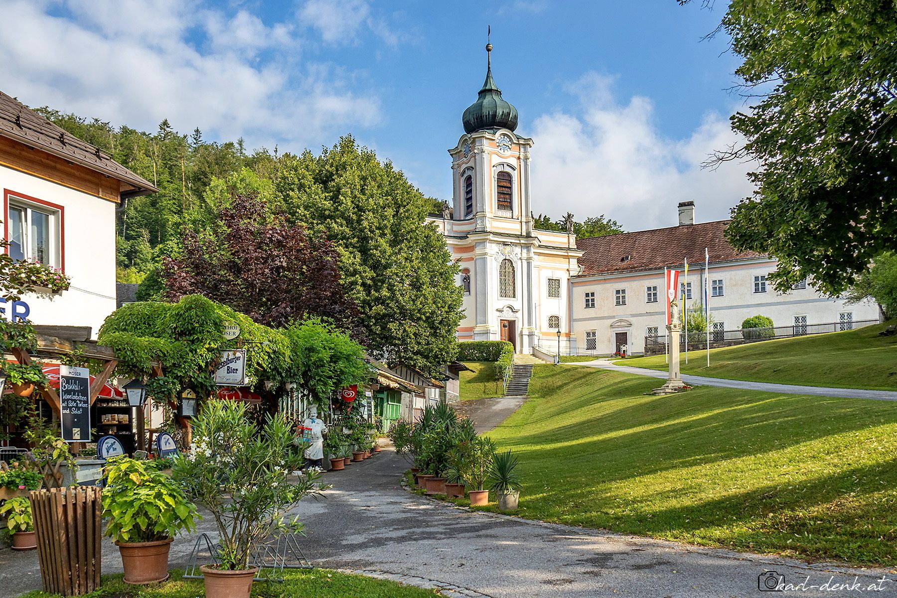 Gasthaus am Weg zu Kirche in einer grünen Landschaft.