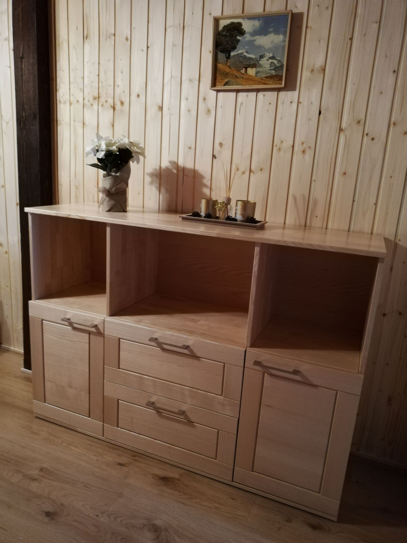 Holzkommode mit Dekoration in einem Raum mit Holzvertäfelung.