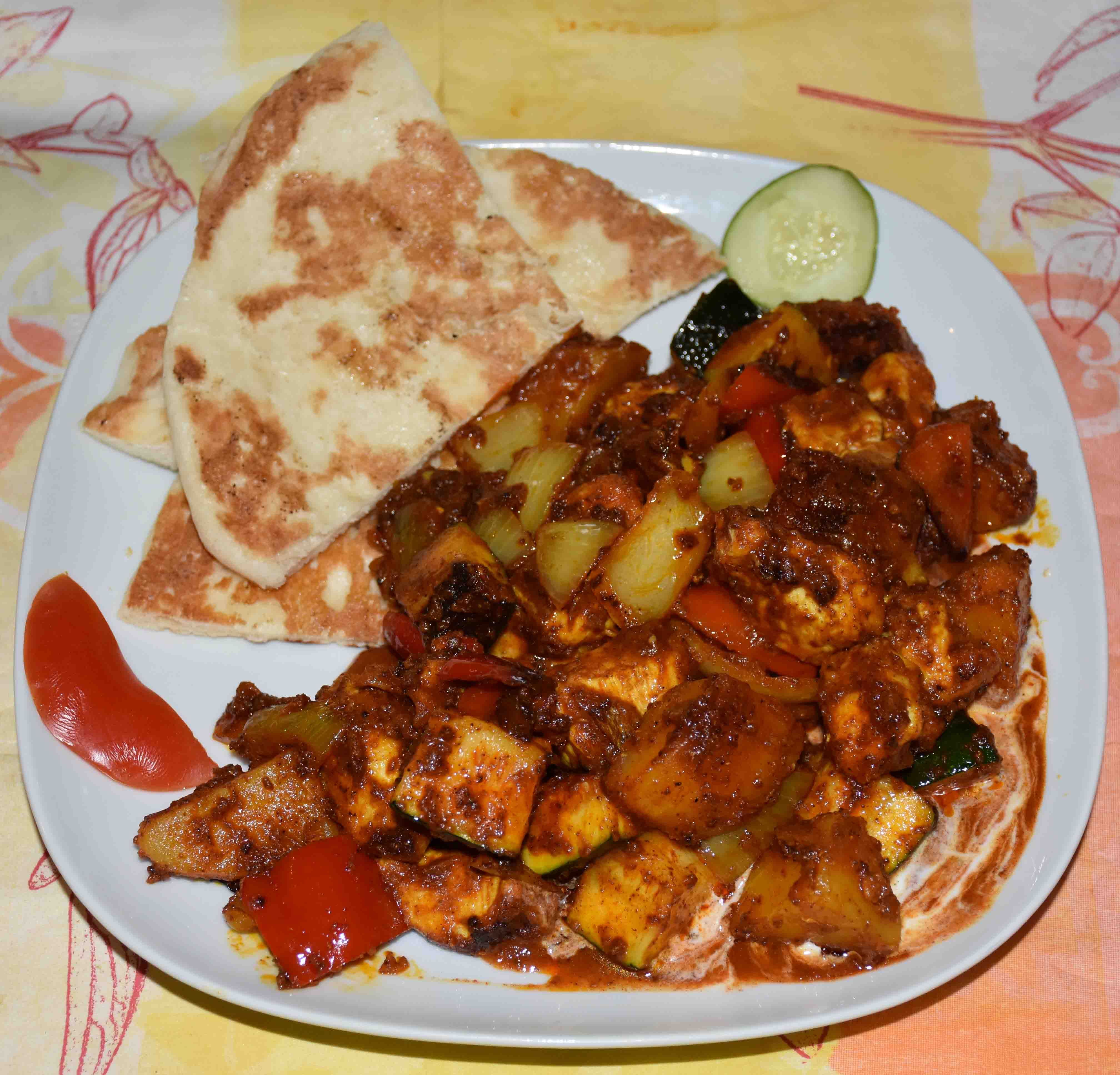 Indisches Gericht mit Naan und gewürztem Gemüse auf einem Teller.