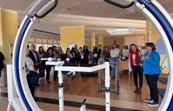 Etwa 20 Personen stehen in Alltagskleidung in einem großen Fitnessraum. 