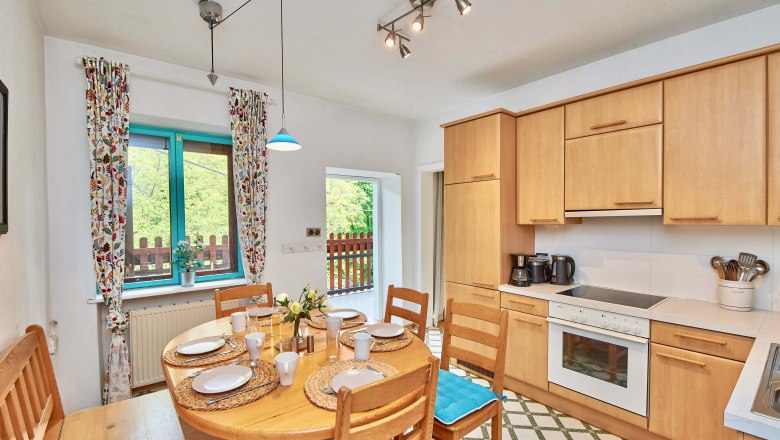 Cozy kitchen with wooden furniture, dining table and window with colorful curtains.