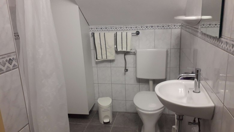 Kleines Badezimmer mit Toilette, Waschbecken und Duschvorhang.