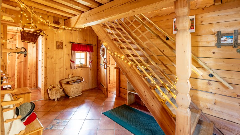 Raum mit Holzvert&auml;felung, Fliesenboden, einer Treppe und Dekoration.