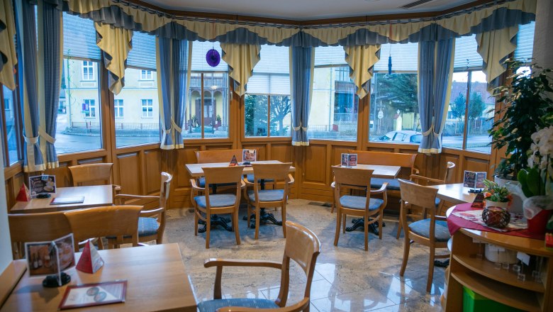 Interior view of a cozy caf&eacute; with wooden furniture and large windows.
