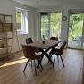 Esszimmer mit Holztisch, braunen St&uuml;hlen und Blick auf Terrasse und Garten.