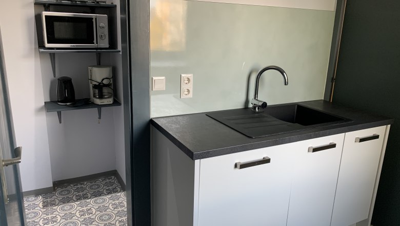 Kleine K&uuml;che mit Sp&uuml;le, Mikrowelle, Toaster und Kaffeemaschine.