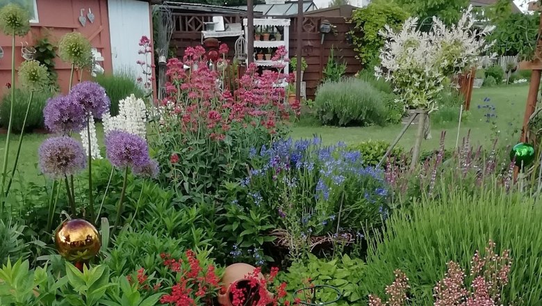 Ein üppiges Staudenbeet mit bunten Blumen und Dekorationen in einem Garten.