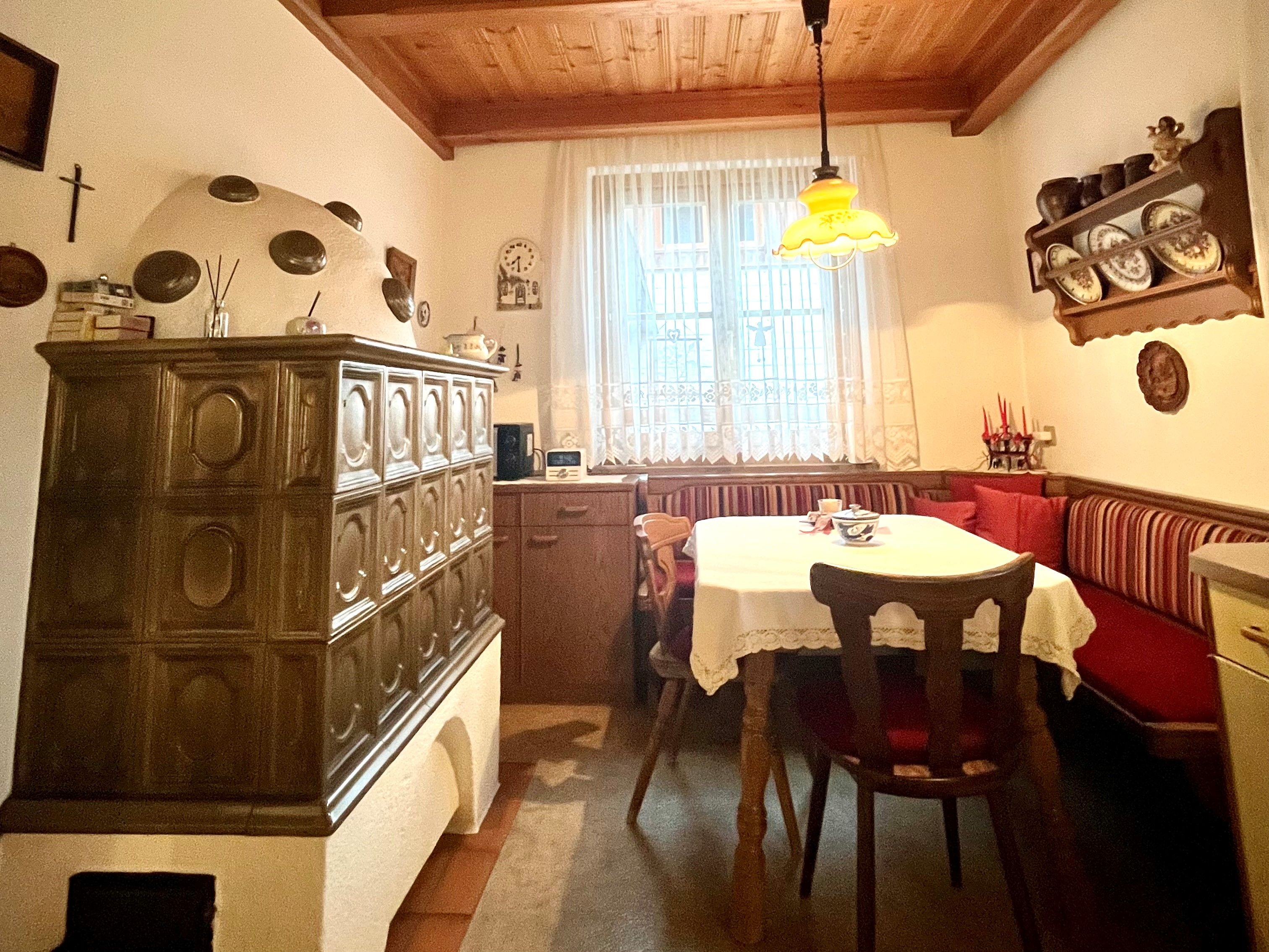 Gemütliche Küche mit Kachelofen, Holztisch und Eckbank.