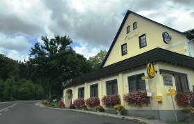 Gasthof Oberer Eggl mit Blumen und Bushaltestelle.