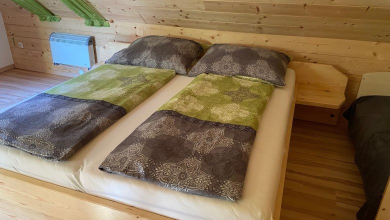 Double bed in a room with wooden paneling and green curtains.