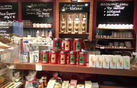 Interior view of a coffee roastery with coffee cans, cups and signs with coffee varieties.