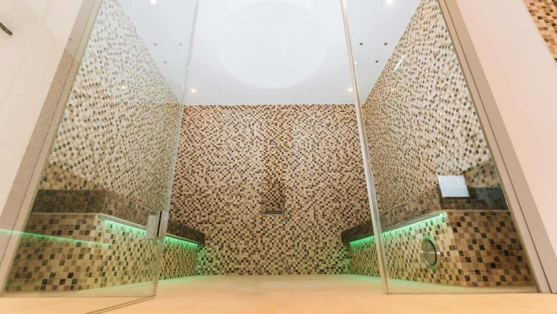 Modern sauna area with mosaic tiles and glass walls.